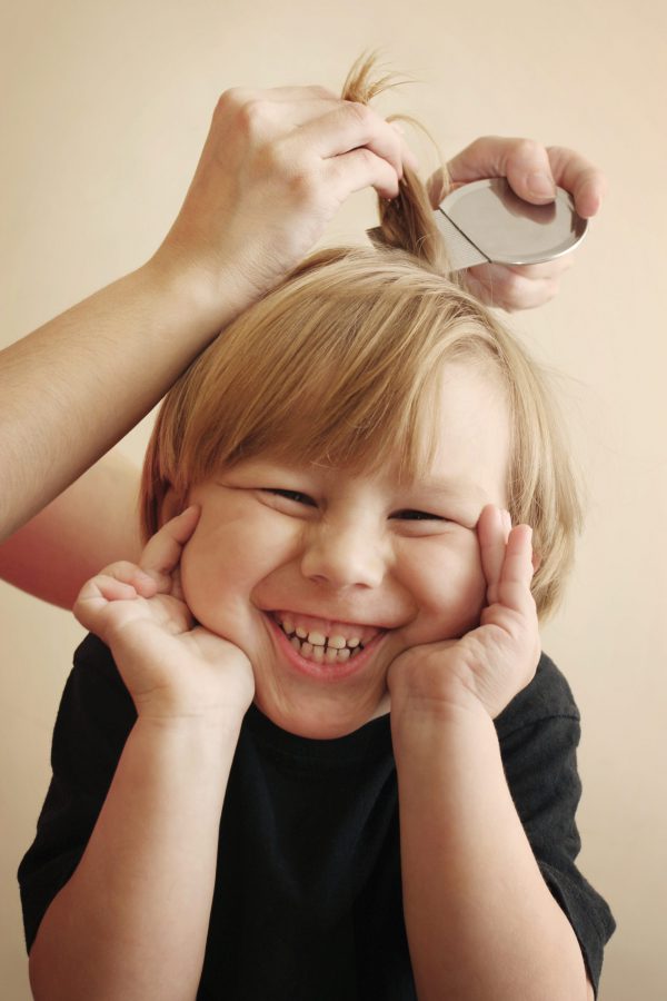 niño sonrie mientras le pasan la liendrera por el pelo