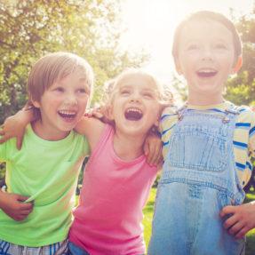 tres niños sonrien abrazados por los hombros